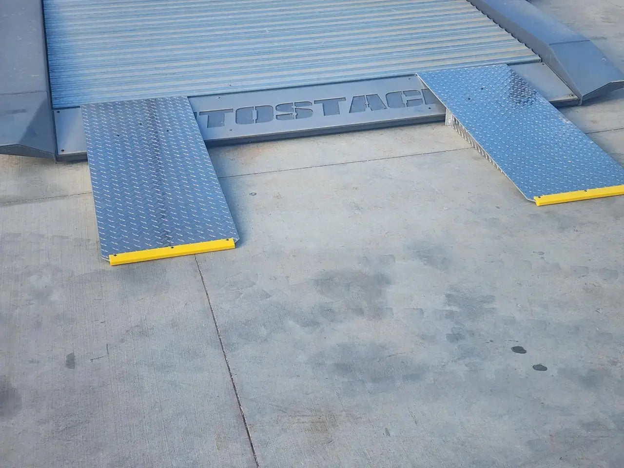 Autostacker 5174106 A6S EXT48 48 in aluminum approach ramps with yellow safety edges shown on lift platform for low clearance vehicle loading