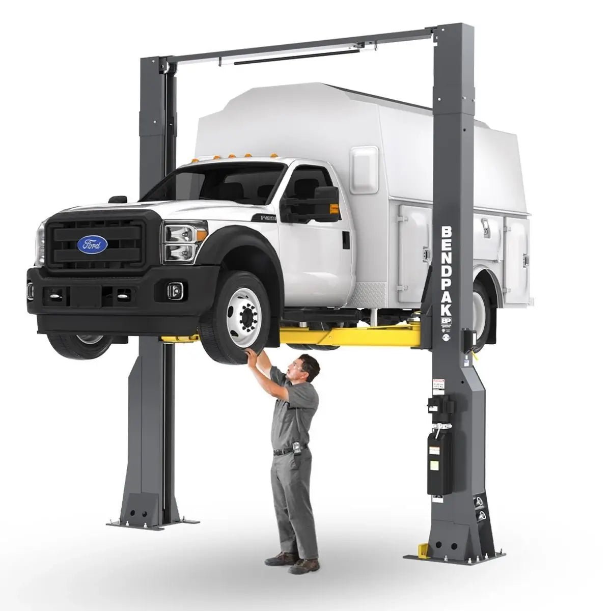 BendPak 20AP-192 two-post lift raising a service truck on white background, technician working below, extended-height clearfloor design with yellow telescoping arms.