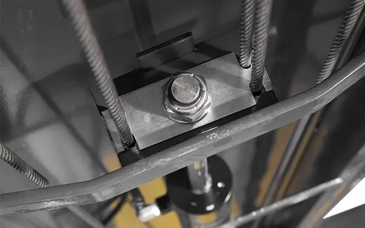 Underside view of BendPak 4-post lift showing single hydraulic cylinder with anti-sway cables and sheave assembly for stable, level lifting performance.