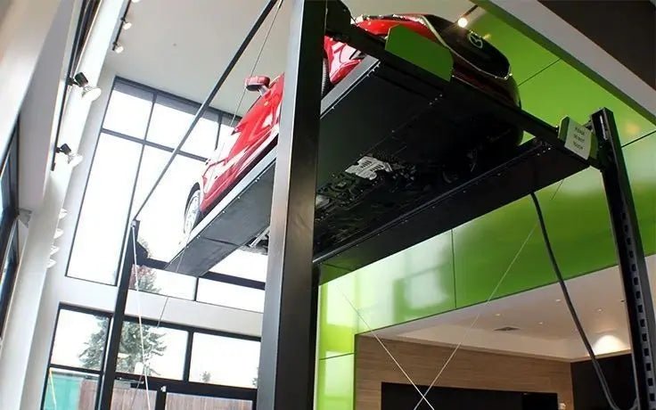 BendPak HD-7PXW four-post car lift installed in a dealership showroom, supporting a red sports car high above the floor to highlight the lift’s extra-tall design for display or storage use.
