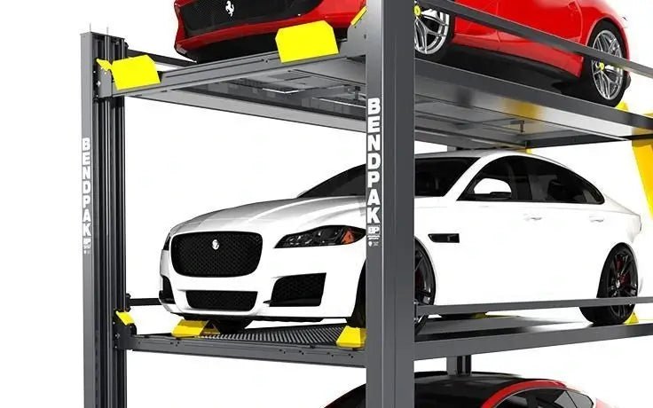 Side view of BendPak HD-973P multi-level parking lift showing three cars stacked vertically — red sports car on top, white sedan in the middle, and part of a black car below — supported by gray steel columns with yellow ramps on a white background.