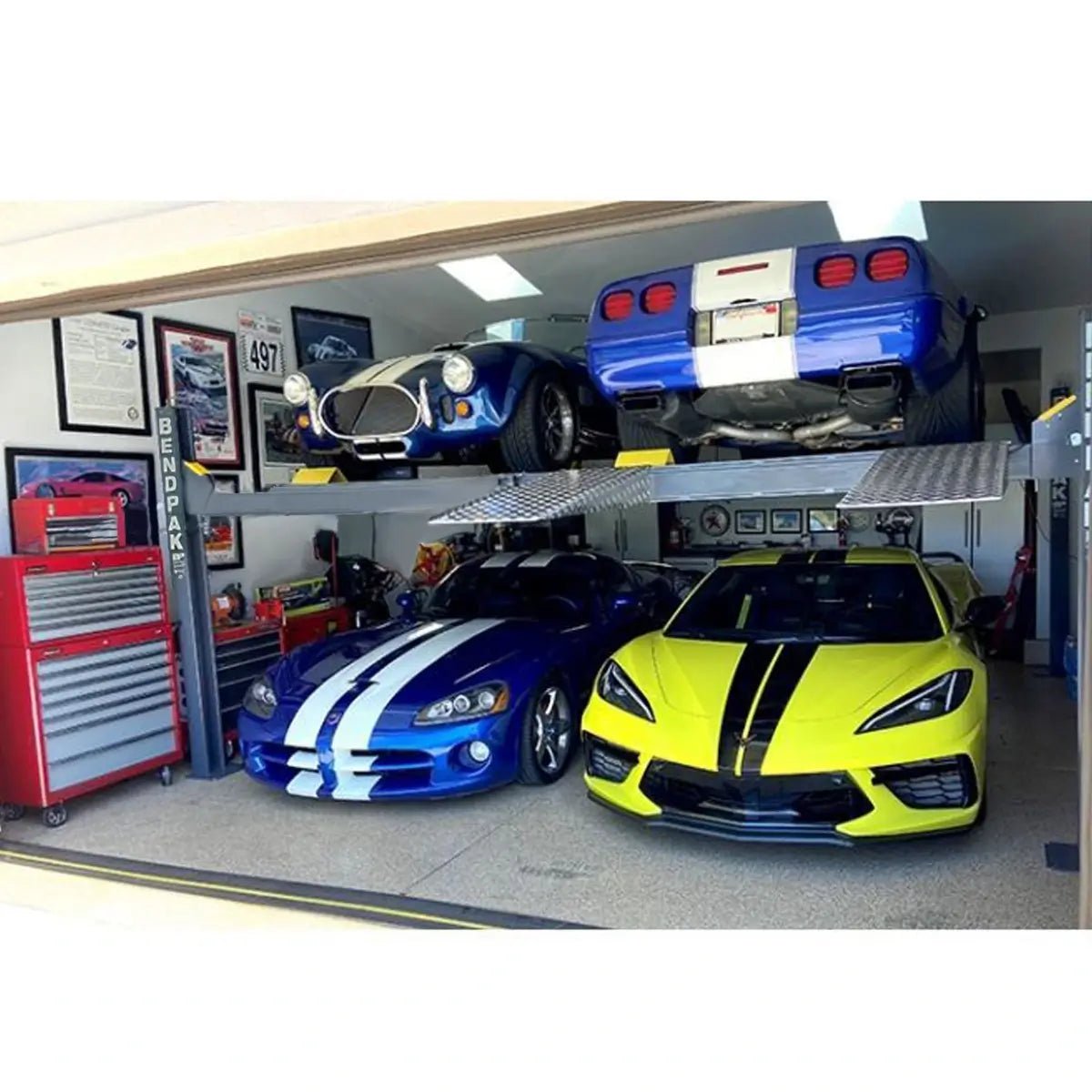 BendPak HD-9SWX four-post lift installed in a home garage showing dual-level parking with four cars, extended height columns, and wide aluminum runways for sports car storage.