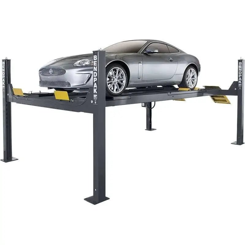BendPak HDS-14LSX alignment lift with silver sports car raised on dual platforms, showcasing ALI-certified four-post design and yellow wheel stops.
