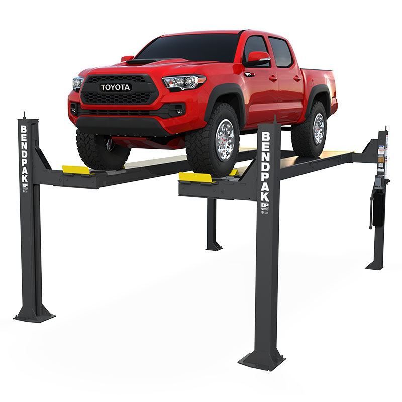 BendPak HDSO14AX open-front four-post alignment lift raising a red Toyota Tacoma pickup, showing full platform and column structure in three-quarter view.