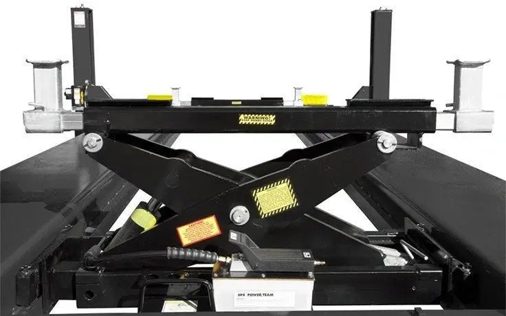 Front view of BendPak RBJ15000 high-capacity rolling bridge jack on four-post lift runways, showing scissor-lift arms, hydraulic cylinder, and adjustable lift pads with black and yellow safety detailing.