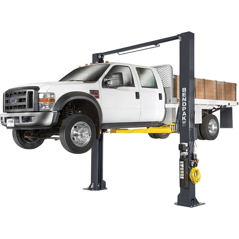 BendPak XPR-12CL-192 two-post lift raising a Ford service truck; hero view highlighting clearfloor design, heavy-duty dual columns, and yellow lifting arms.