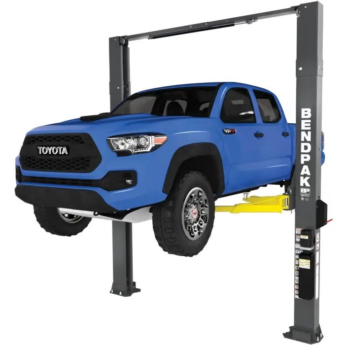 BendPak XPR-18CL-192 two-post lift raising a white service truck; hero view shows clearfloor design, yellow arms, and overhead top beam with safety bar.