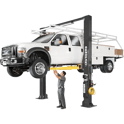 BendPak XPR-18CL two-post lift raising a white Ford service truck; hero angle highlights clearfloor design, overhead beam, and yellow lift arms in operation.