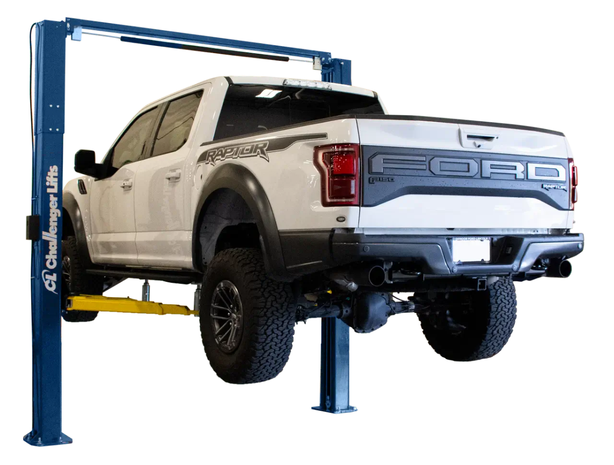 Challenger VLE10 two post lift raising a white Ford Raptor pickup, demonstrating heavy duty 10000 lb lifting capacity and dual position arm design for trucks