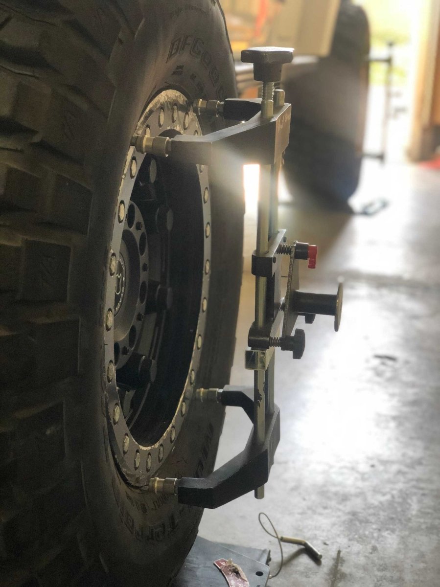 TRU-LINE TL-12DELUXE alignment equipment attached to a light truck wheel showing clamps and sensors.