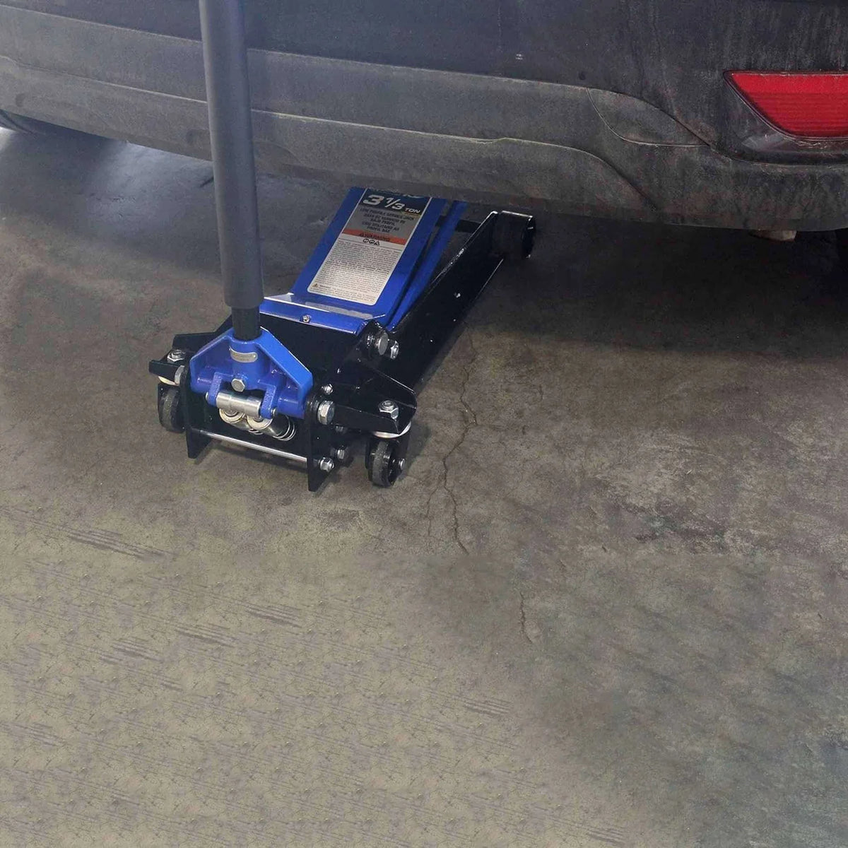 K-Tool XD63133 low profile service jack rolled under a vehicle rear bumper on a shop floor