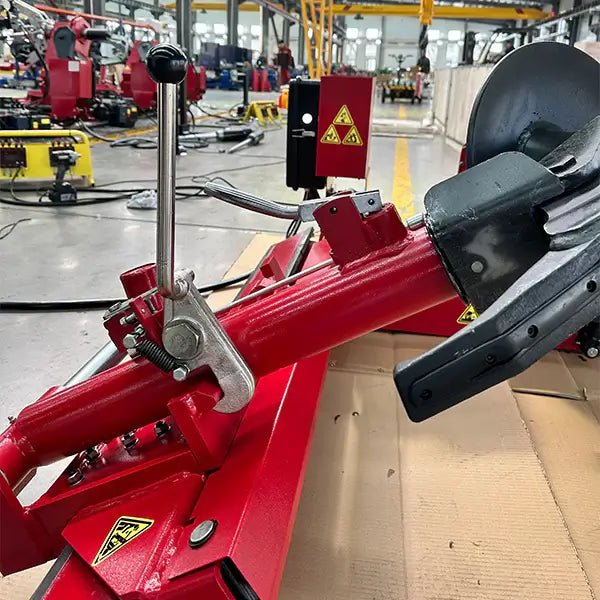 Katool KT-T160 truck tire changer close-up of bead press arm with lever handle and roller disc, mounted on red carriage frame in factory setting.