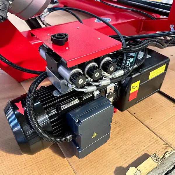 Katool KT-T160 truck tire changer close-up of hydraulic power unit with electric motor, fluid reservoir, control valves, and wiring connections.