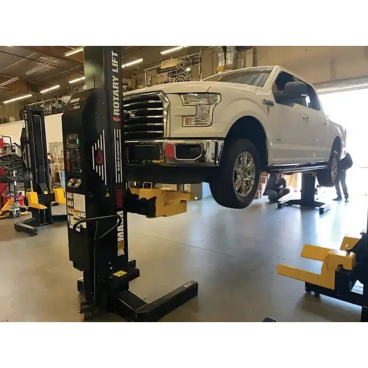 White Ford F-150 on black column lift with Rotary M140168YL cross beam kit