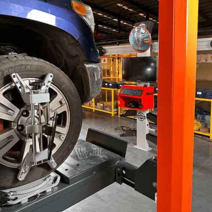 Katool AV533 3D wheel alignment machine in use during vehicle alignment, showing sensor targets attached to wheel and alignment system with monitor and control unit