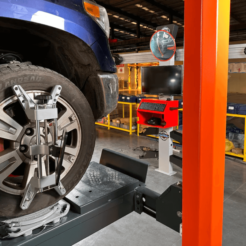 Katool AV533 3D wheel alignment machine in use during vehicle alignment, showing sensor targets attached to wheel and alignment system with monitor and control unit