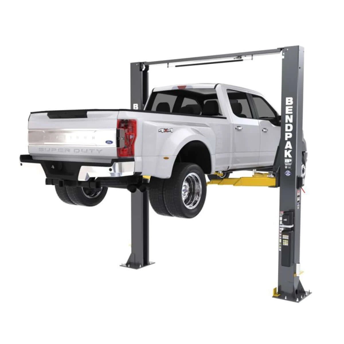 BendPak 12APX two-post lift holding a white pickup truck, rear angle view.