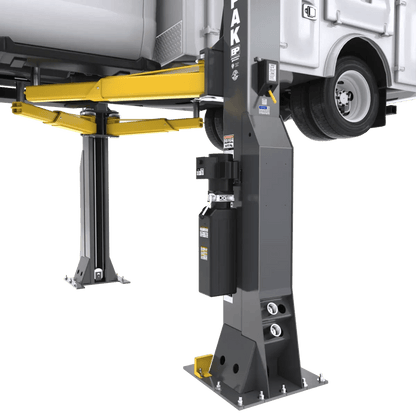BendPak 20AP-192 two-post lift closeup of multi-face column showing power unit mount, hydraulic lines, yellow lift arms, and heavy-duty base structure supporting raised truck.