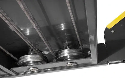 Close-up underside view of BendPak HD-14T four-post lift showing large cable sheave design with heavy-duty steel cables and pulleys that reduce wear and ensure balanced lifting performance.