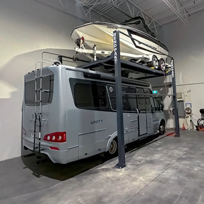 BendPak HD-7500PBX high-rise four-post boat and vehicle storage lift in warehouse use, holding a large white powerboat on the upper platform with a silver Unity RV parked below, showcasing tall steel columns, heavy-duty runways, and industrial-grade structure inside a modern facility.