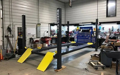 BendPak HD-7P four-post car lift installed in an automotive workshop, showing the lift structure, ramps, and sturdy HD-Series design ideal for service bays and vehicle storage.