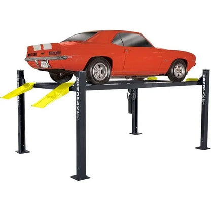 BendPak HD-9ST four-post lift studio hero view with red classic car on short runways, showing four columns, yellow ramps, and BENDPAK branding.