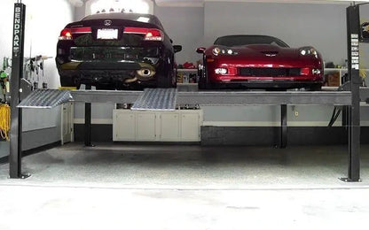 BendPak HD-9SW four-post lift installed in a garage showing two cars parked side by side on wide runways with four columns and yellow ramps.