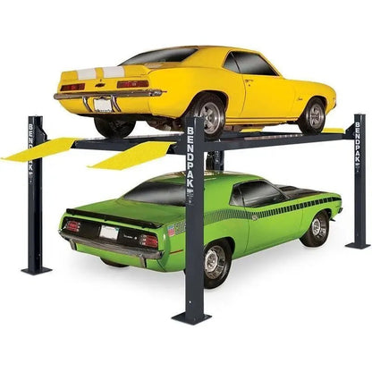BendPak HD-9XL four-post lift with a yellow muscle car elevated above a green car, showing the extended runways, yellow drive-on ramps, and heavy-duty steel columns for vehicle storage or maintenance.