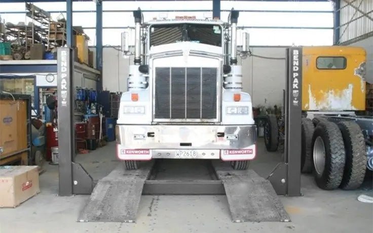 Front view of a BendPak HDS-40 heavy-duty four-post lift raising a large semi-truck inside a commercial service garage, showcasing its industrial strength and 40,000-lb lifting capacity.
