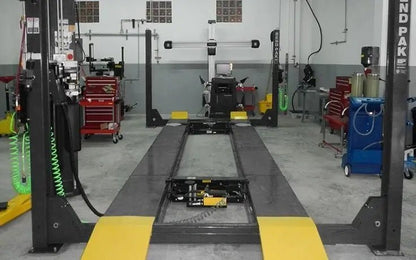 BendPak HDS-14LSX four-post alignment lift installed in service facility, showing dual units with yellow ramps and alignment console setup.