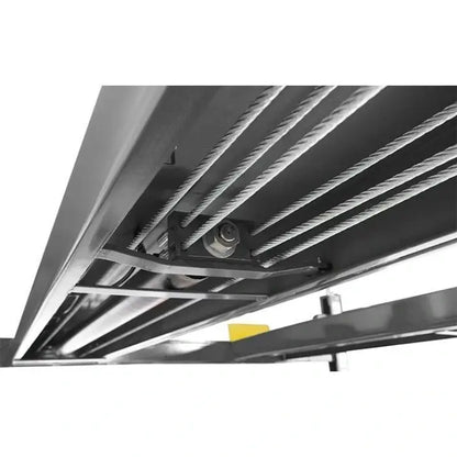 BendPak HDSO14P four-post lift underside view showing steel cable routing and pulleys for synchronized platform lifting operation