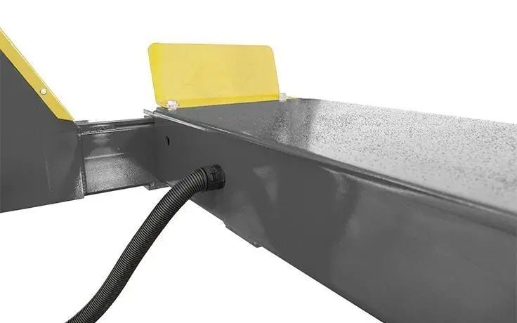 BendPak HDSO14P four-post lift platform showing routed hydraulic line with protective sleeve and yellow wheel stop.