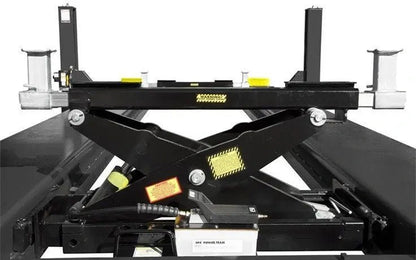 Front view of BendPak RBJ15000 high-capacity rolling bridge jack on four-post lift runways, showing scissor-lift arms, hydraulic cylinder, and adjustable lift pads with black and yellow safety detailing.