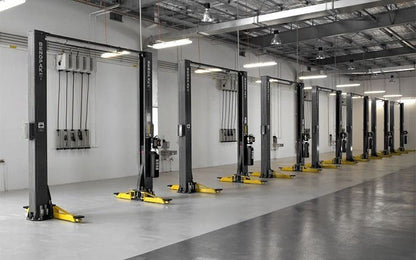 BendPak XPR-12CL-192 two-post lifts installed in commercial service bays; wide view showing multiple clearfloor units with overhead hydraulic routing