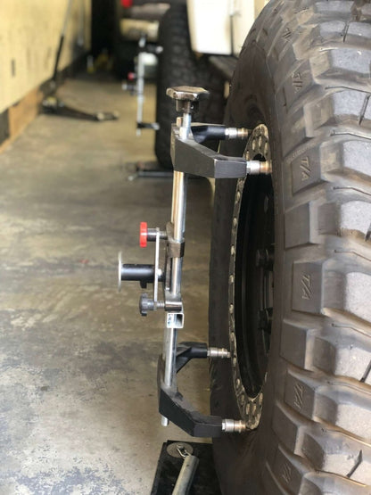 TRU-LINE TL-12DELUXE laser alignment system mounted on a passenger vehicle wheel in a garage setting.