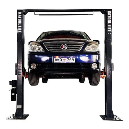 Katool AM120SD 12,000 lb 2-post clear-floor car lift with vehicle raised, front view.