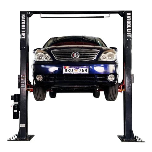 Katool AM120SD 12,000 lb 2-post clear-floor car lift with vehicle raised, front view.