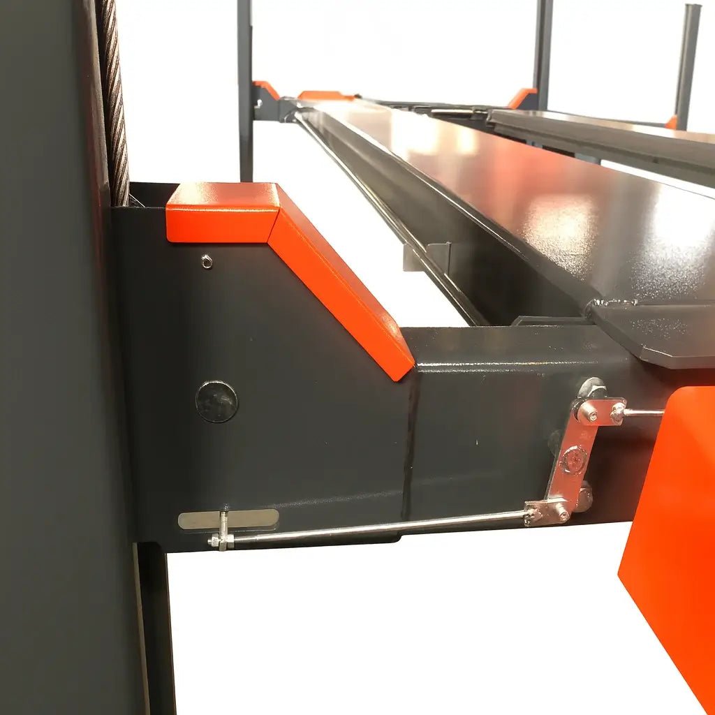 Katool KT-4H110 11,000 lb 4 post lift, close-up of the mechanical safety lock assembly showing the orange cover, metal linkage, and cable guide along the runway edge on a white background.